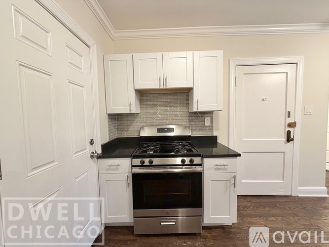 A kitchen with white cabinets and a black countertop.
