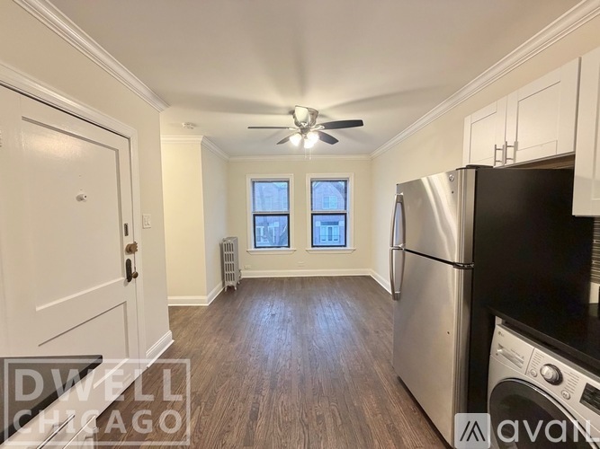 A kitchen with a stainless steel refrigerator and a washer and dryer unit.