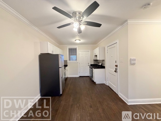 A spacious kitchen with a black refrigerator and white cabinets.