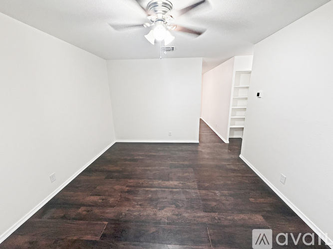 A room with a ceiling fan and wooden flooring.