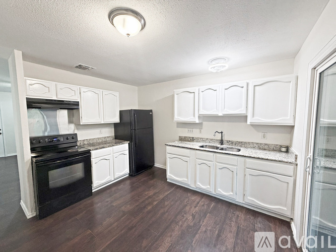 A kitchen with black appliances and white cabinets.