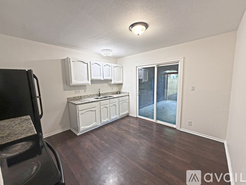 A kitchen with white cabinets and a black chair.