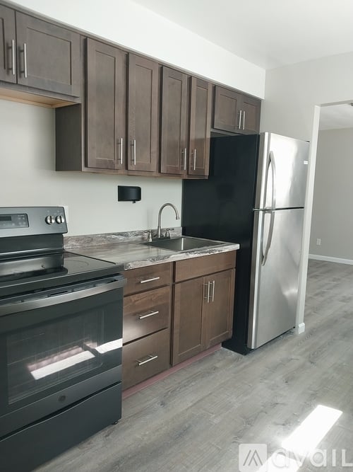 A kitchen with a black refrigerator and a stove top oven.