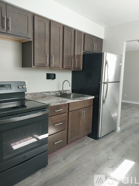 A kitchen with a black refrigerator and a stove top oven.
