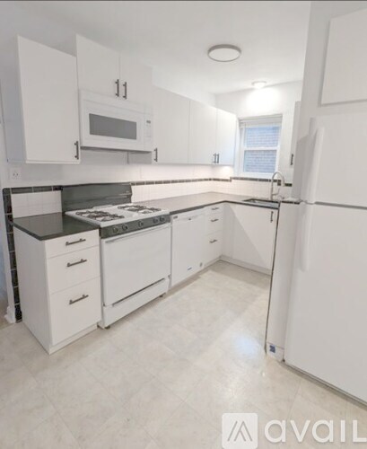 A kitchen with white cabinets and appliances, including a refrigerator, oven, and microwave.