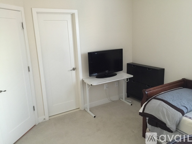 A bedroom with a bed, dresser, and a television on a stand.