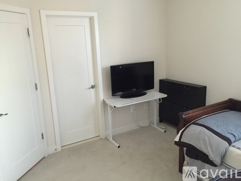 A bedroom with a bed, dresser, and a television on a stand.