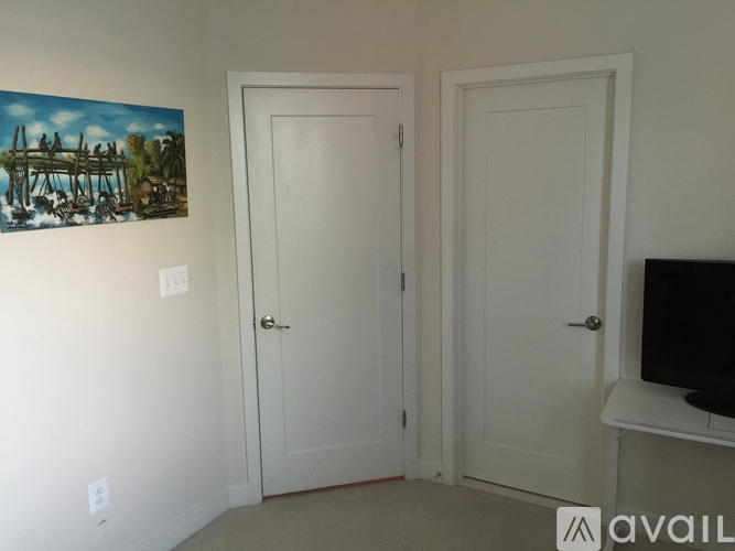 A room with two doors and a painting on the wall.