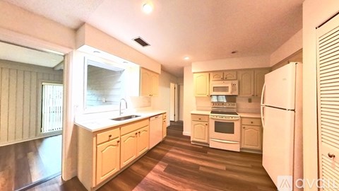 A kitchen with wooden floors and white appliances.