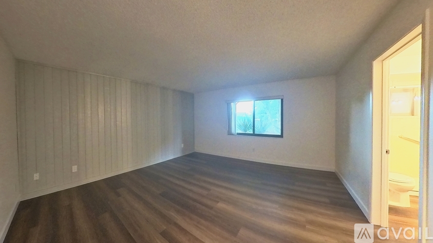 A room with wooden floors and a window with a view of trees.