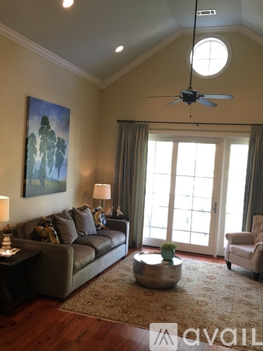 A living room with a couch, a fan, and a painting on the wall.