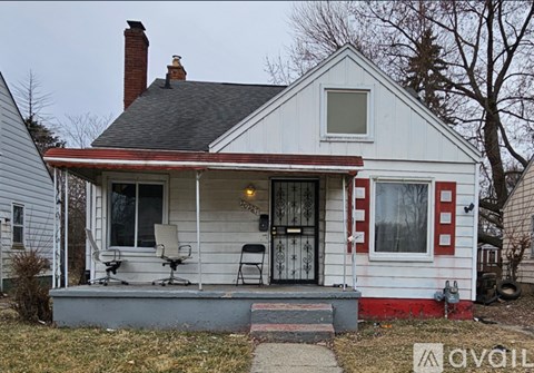 A small white house with a red trim and a black door.