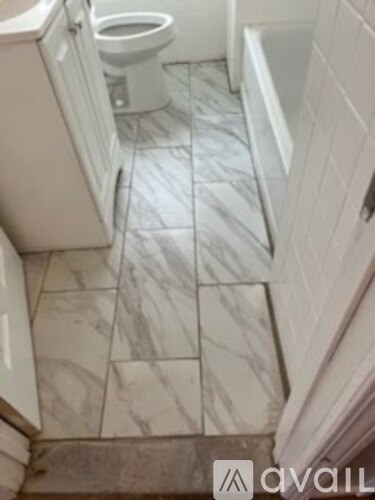 A bathroom with a toilet and a marble floor.