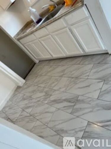 A kitchen with a marble floor and white cabinets.