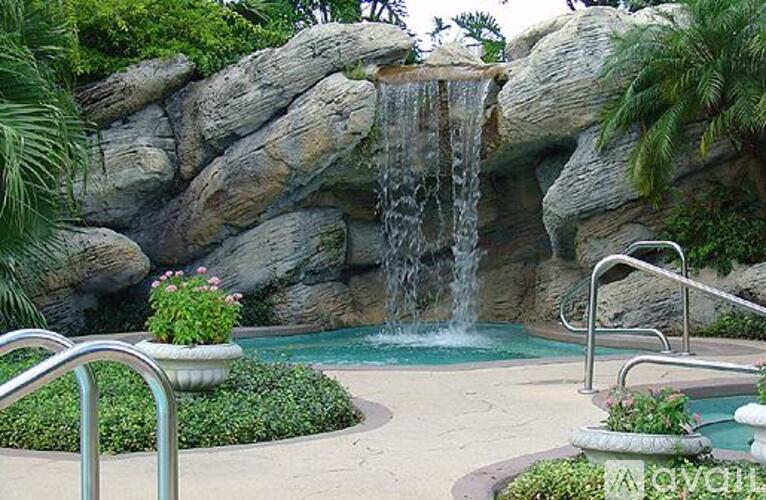 A pool with a waterfall and a rocky background.