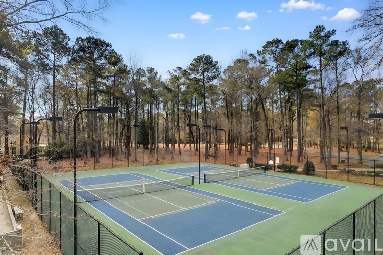 A tennis court surrounded by trees and a fence.