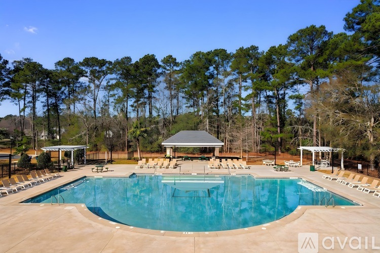 A large swimming pool surrounded by trees and a pavilion.