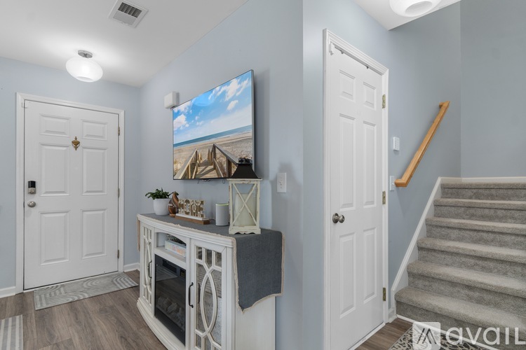 A living room with a television on the wall and a staircase in the background.