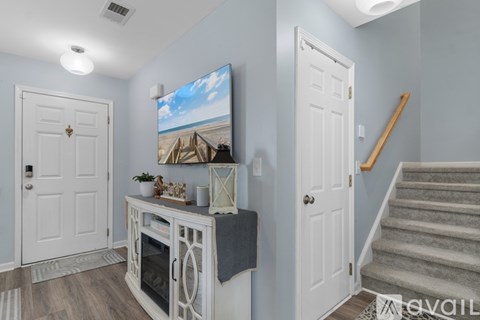 A living room with a television on the wall and a staircase in the background.