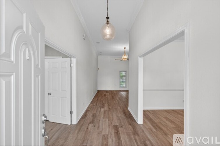 A hallway with a wooden floor and white walls.