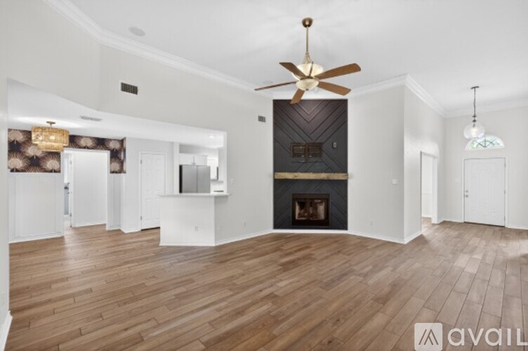A spacious living room with a fireplace and a ceiling fan.
