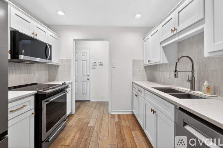 A kitchen with white cabinets and a wooden floor.