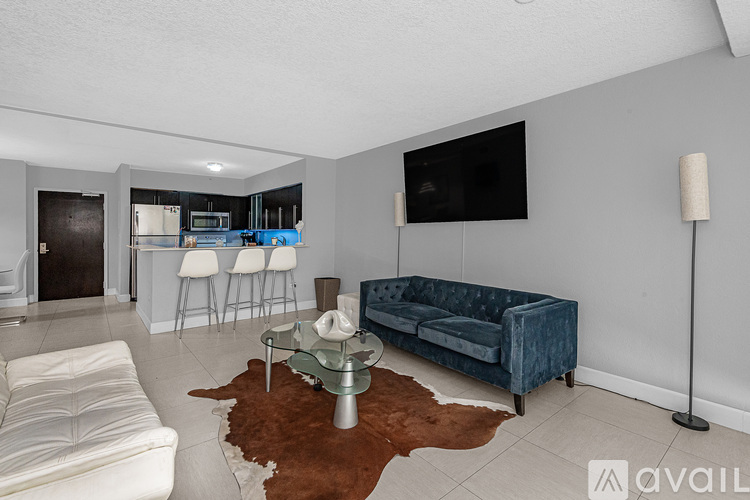 A living room with a blue couch and a television mounted on the wall.