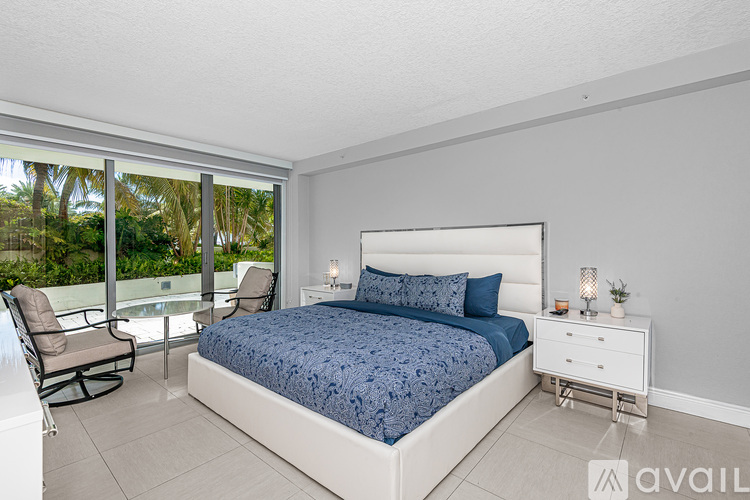 A bedroom with a large bed, a chair, and a nightstand with a lamp.