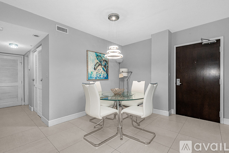 A dining room with a glass table and white chairs.
