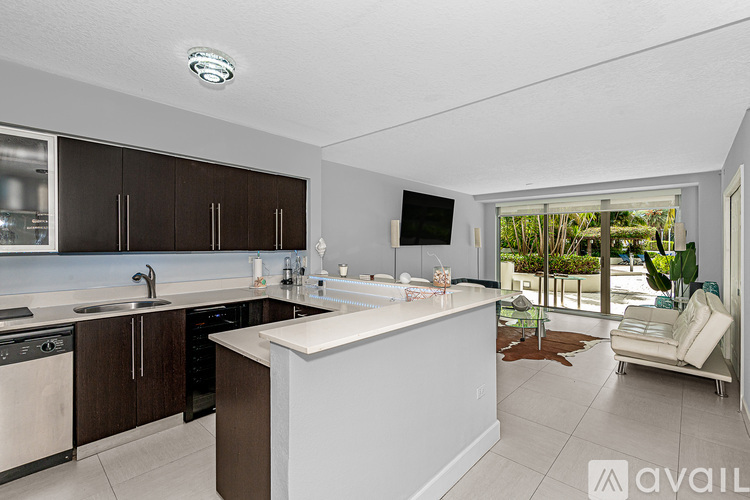 A modern kitchen with dark brown cabinets and white countertops.