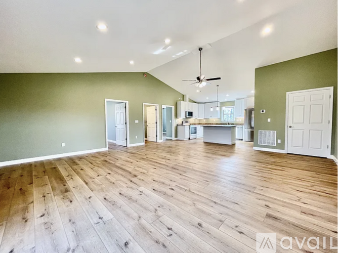 A spacious room with wood flooring and a ceiling fan.
