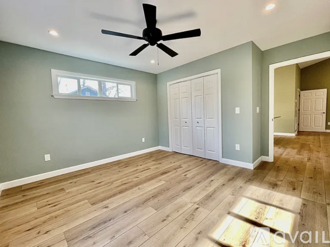 A room with a ceiling fan and wooden flooring.