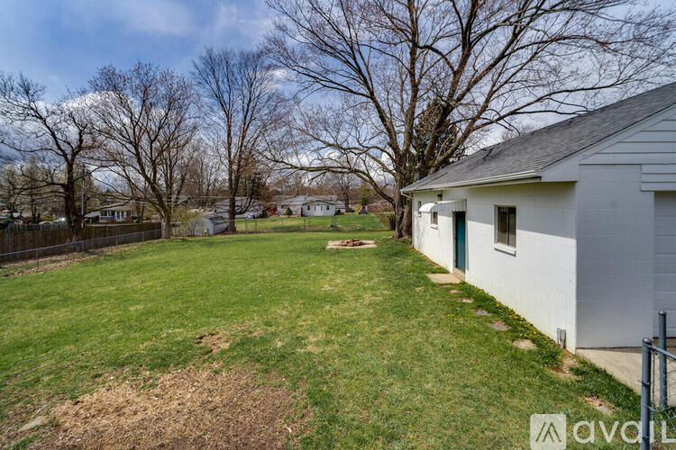 A white house with a green door is surrounded by a grassy yard.