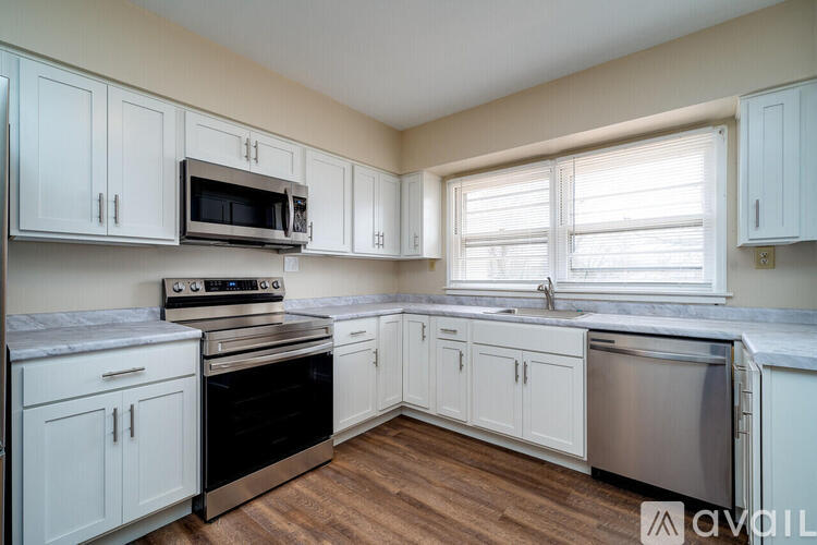 A kitchen with white cabinets and a wooden floor.