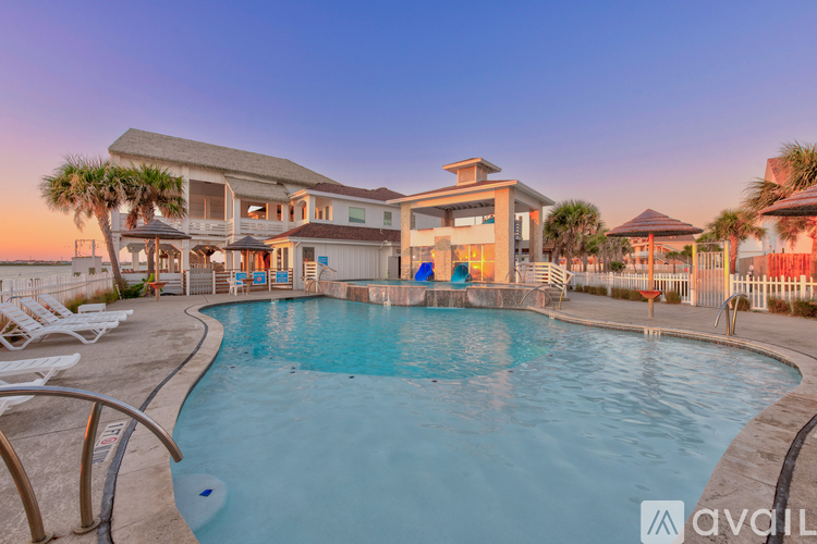 A large swimming pool in front of a house with a sunset in the background.