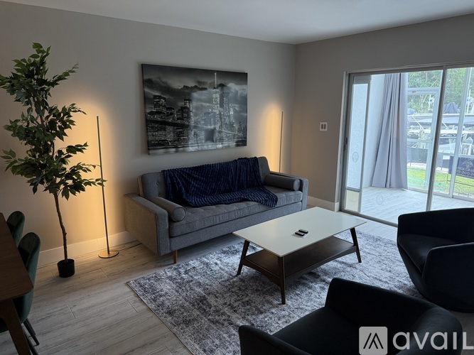 A living room with a grey couch, a coffee table, and a painting on the wall.