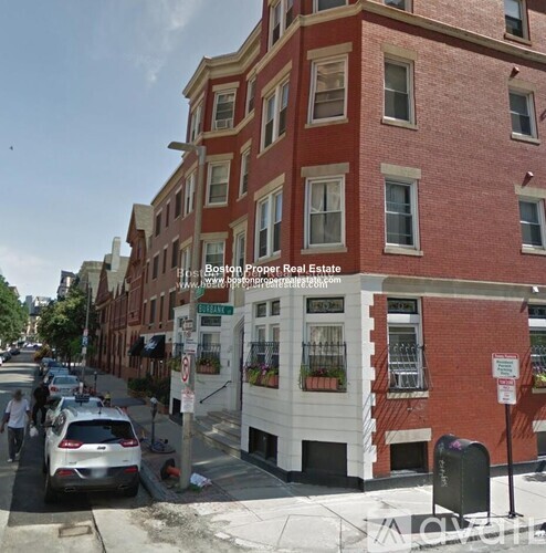 A street view of a red brick building with a car parked in front.