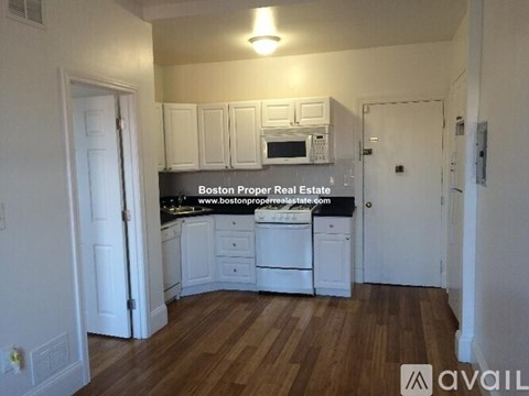 A kitchen with white cabinets and a wooden floor.