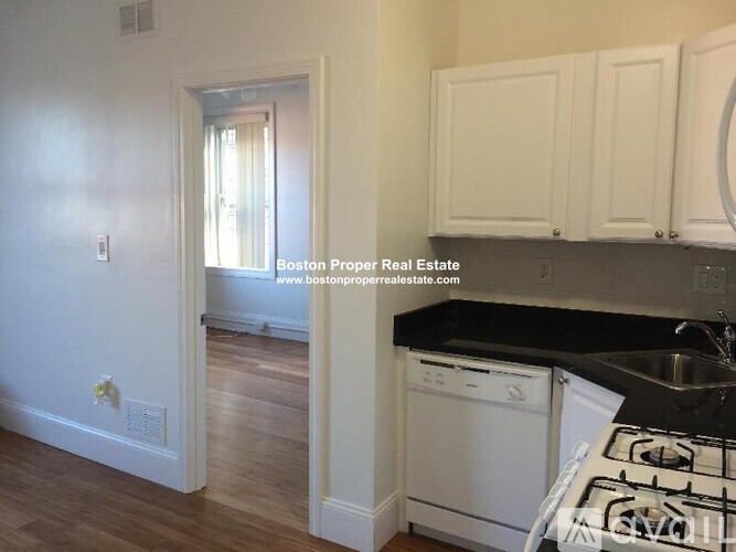 A kitchen with white cabinets and a black counter top.