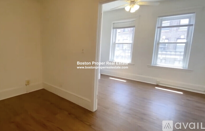 A room with wooden floors and two windows, one of which is open.