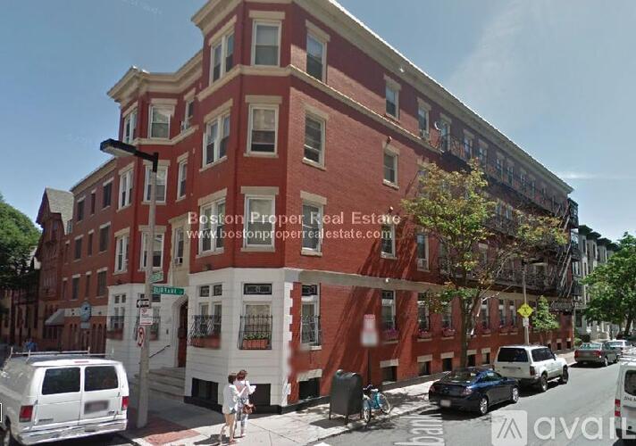 A street view of a red brick building with the text "Boston Proper Real Estate" on it.