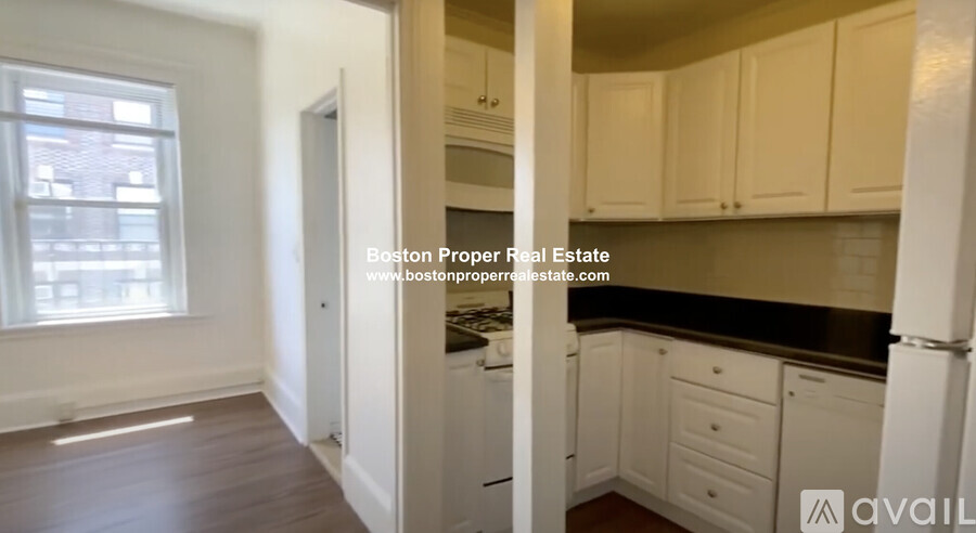 A kitchen with white cabinets and a window.