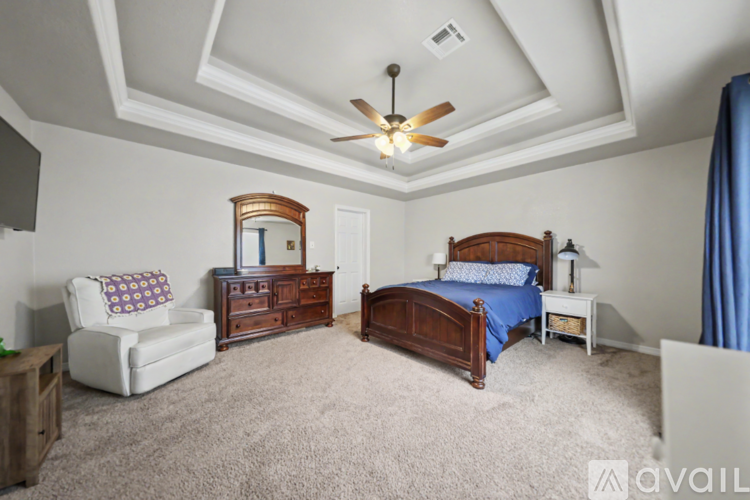 A bedroom with a bed, chair, and a ceiling fan.