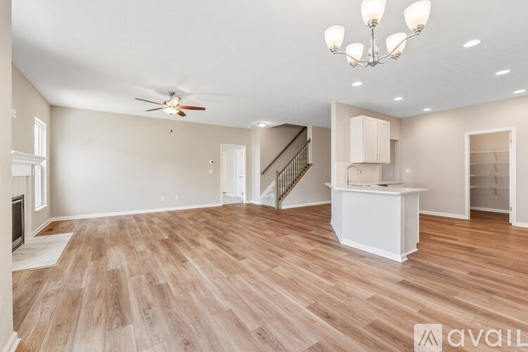 A spacious room with wooden flooring and a staircase.