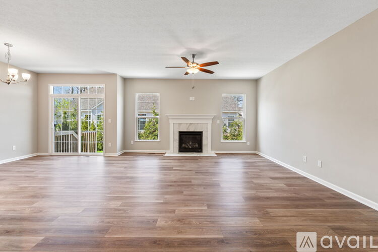 A spacious living room with wood flooring and a fireplace.