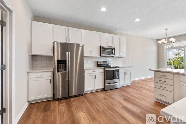 A kitchen with white cabinets and a wooden floor.