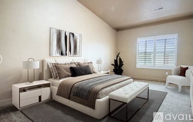 A bedroom with a large bed, a nightstand with a lamp, and a chair.