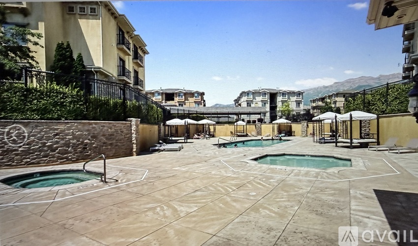 A large outdoor pool area with a hot tub and lounge chairs.