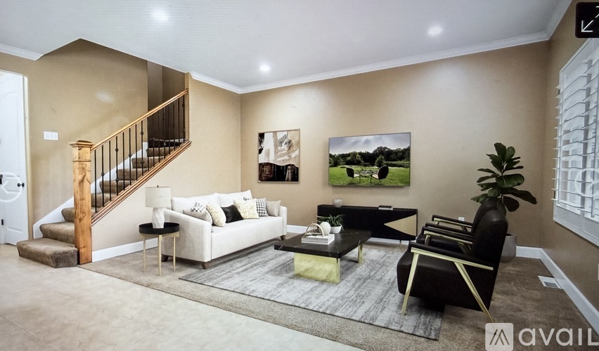 A living room with a white couch, a coffee table, and a staircase.