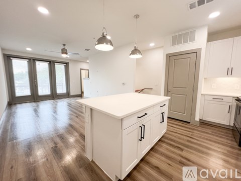 A kitchen with white cabinets and a wooden floor.